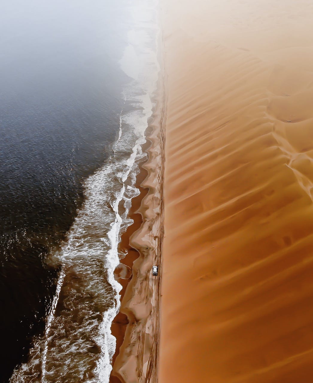 Dunes meeting the Atlantic near Swakopmund, where the Namibian coast stays cool while inland reaches 36C