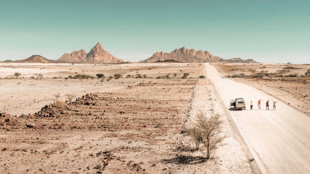 A vehicle on a gravel road with granite peaks beyond